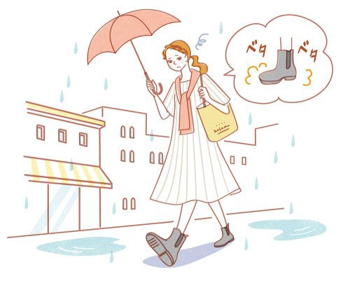 雨の中傘をさして歩くブーツを履いた女性